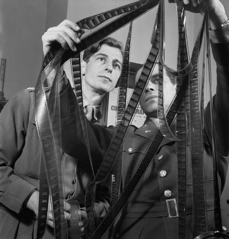 Colonel Frank Capra right of the US Army Signal Corps confers with Captain Roy Boulting of the British Army Film Unit on the editing of the film Tunisian Victory in February 1944. D18377